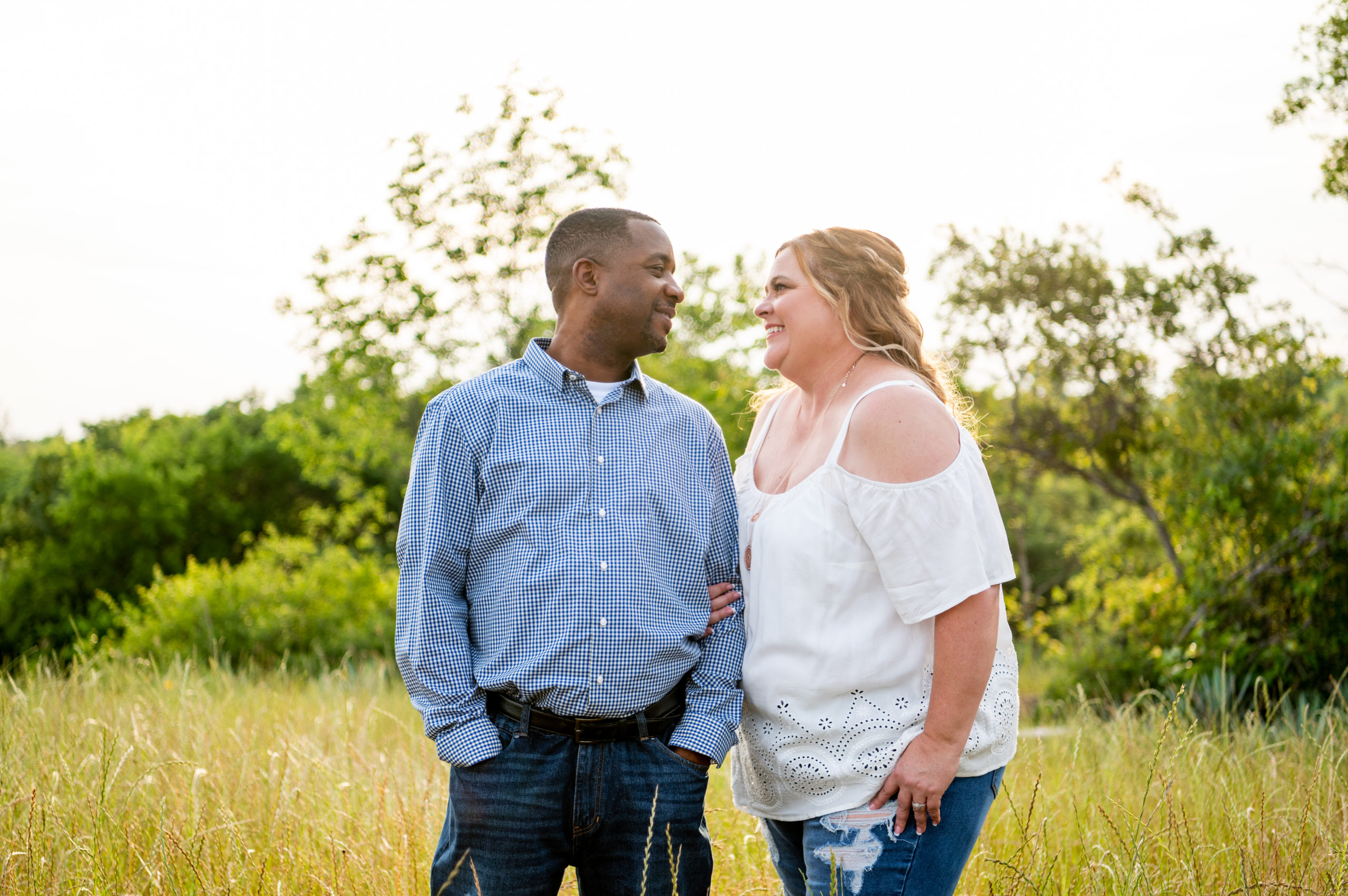 Engaged couple smiling at each other in a field