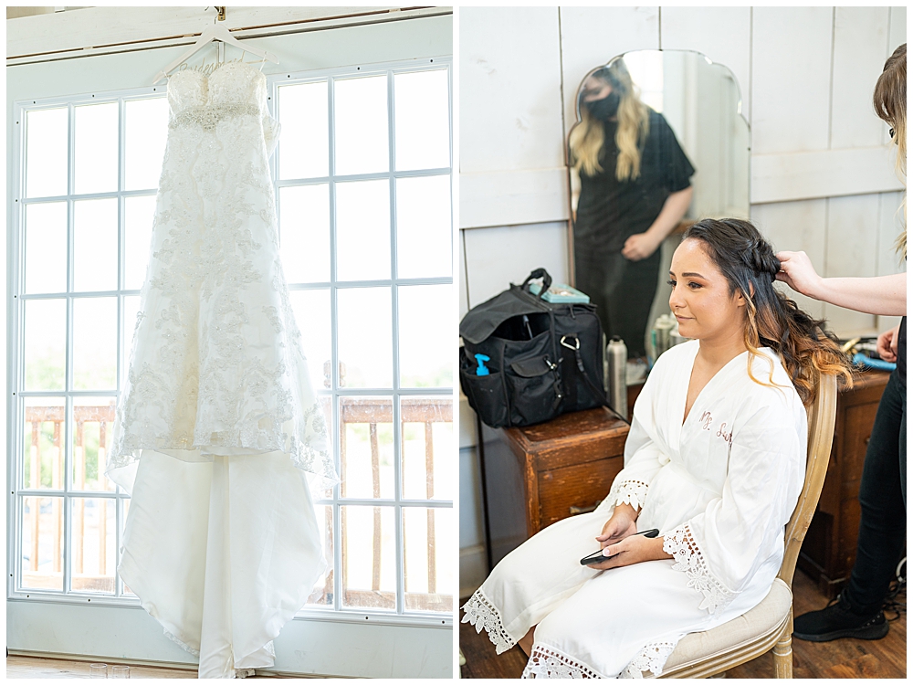 Bride getting hair done with dress hanging beside her